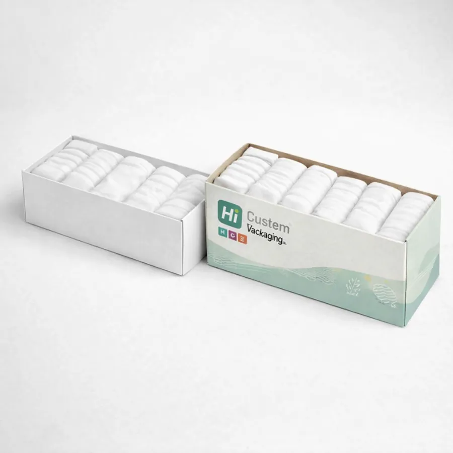 Two wide rectangular boxes filled with several neatly rolled white vests- displaying brand logos on one- class=